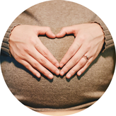Picture of hands making a heart on a pregnant belly